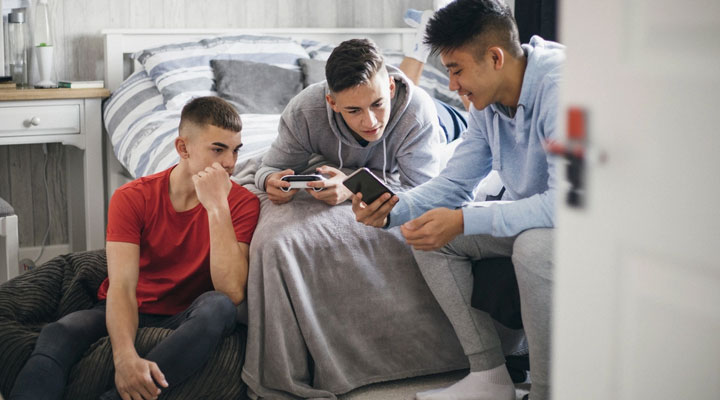 اهمیت آموزش مسائل جنسی به کودکان + راهنمای آموزش در سنین مختلف 4 آموزش مسائل جنسی به نوجوانان ـ چند نوجوان در حال صحبت و کندوکاو در اینترنت